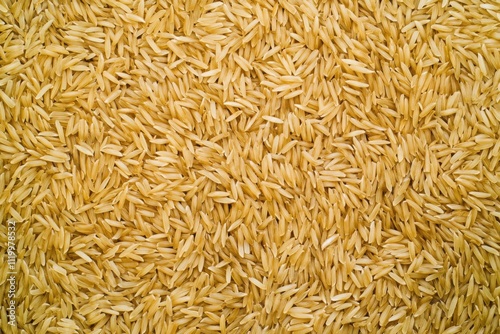 Golden uncooked rice grains spread out on flat surface ready for storage or cooking