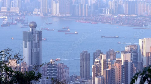 Buildings stand against the water during the daytime in Hong Kong with a view of the big ships
