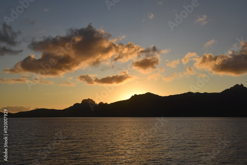 Stunning Pacific Ocean sunset with beams of colourful light shining up from the sea and islands in Fiji