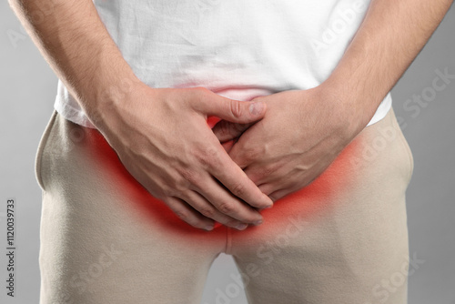 STD (sexually transmitted diseases). Man holding hands near his groin on grey background, closeup