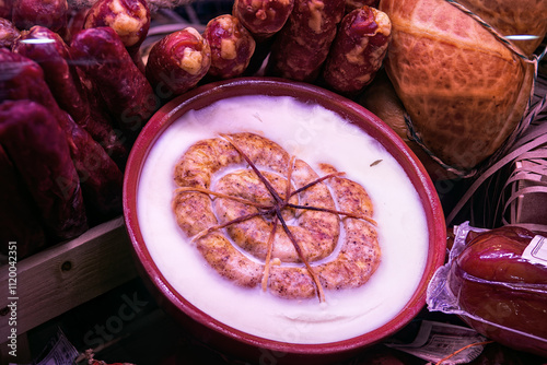 Traditional homemade ring sausage in solidified pork fat in gift ceramic bowl top view. Traditional sausages are sale in butcher shop.