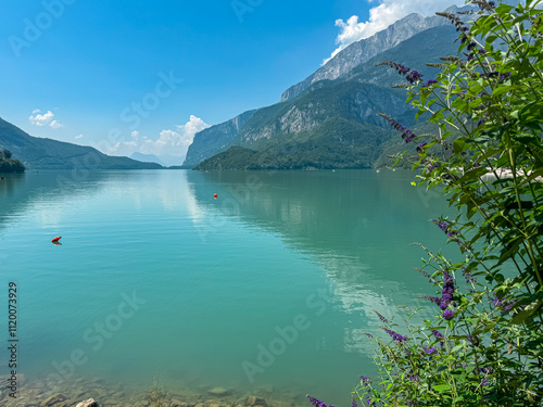 Tree branches framing idyllic mountain lake Lago di Molveno with scenic view of majestic mountains Brenta Dolomites, National Park Adamello Brenta, Trentino, Italy. Serene summer lakeside atmosphere photo