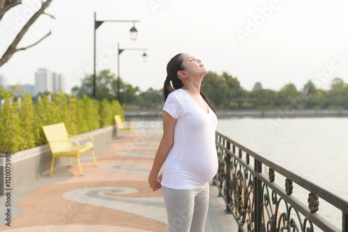 Beautiful pregnant woman stretching and exercising in the park