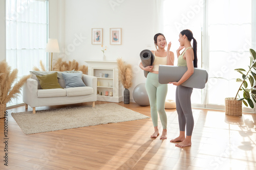 Two young Asian woman friends relaxing after doing Yoga at home.