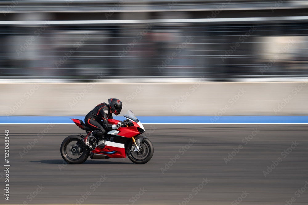 Motorcycle rider riding on a red sport bike through the corner at high speed. Motorcycle rider riding on a red sport bike through the corner at high speed.