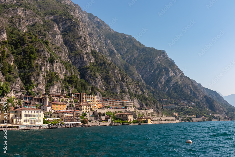 Scenic view of picturesque lakeside town Limone Sul Garda, Lombardy, Northern Italy. Tranquil atmosphere on Garda Lake surrounded by majestic rugged mountains and cliffs of Garda Hills. Summer travel Scenic view of picturesque lakeside town Limone Sul Garda, Lombardy, Northern Italy. Tranquil atmosphere on Garda Lake surrounded by majestic rugged mountains and cliffs of Garda Hills. Summer travel