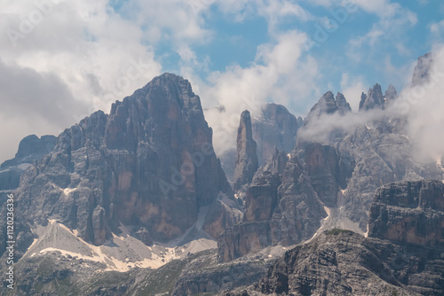 Fotografie Panoramic view of cloud covered rocky rugged mountain peaks of majestic Brenta Dolomites, Trentino, Italy