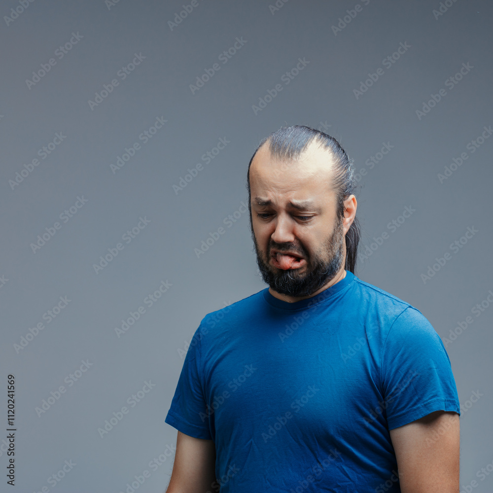 Man showing disgust sticking out tongue on gray background Man showing disgust sticking out tongue on gray background