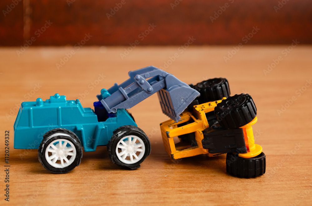 Fototapeta premium A small toy excavator turns over a car