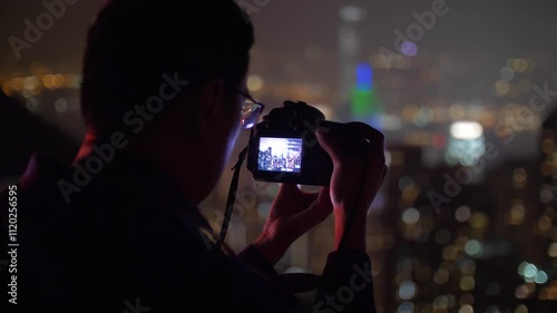 Man takes photos of Hong Kong and Victoria Harbour at night. Big city lights