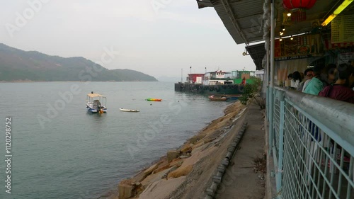 A small boat floats on the water against the backdrop of buildings in Hong Kong during the daytime from a building view