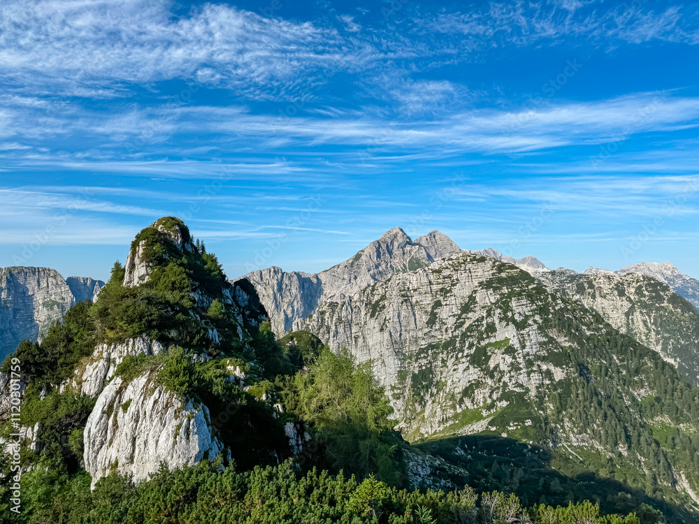 Obraz premium Scenic view of pristine rugged mountain peaks of Kanin massif, Julian Alps, Italy, Europe. Wild hiking trail along majestic ridges in Triglav National Park. Wanderlust alpine wilderness in summer. Awe