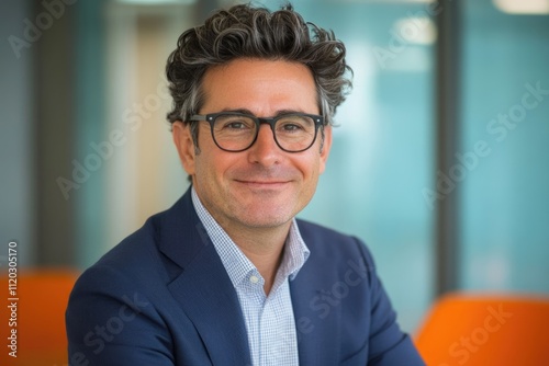 A smiling man in glasses and a blue blazer, a professional portrait.