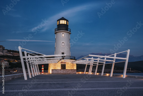 Modern lighthouse stands tall, its light piercing the twilight sky, guiding ships along the coastline photo