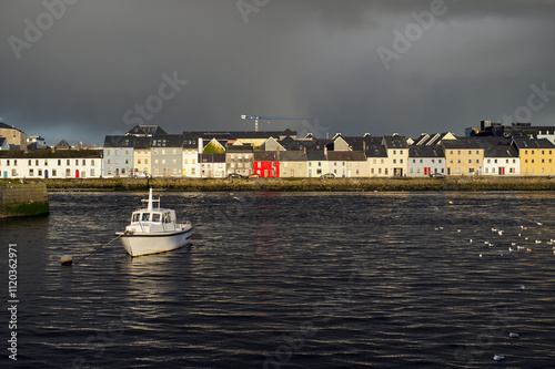 Obraz na płótnie Beautiful cityscape sunrise scenery with old wooden boat in Corrib river at Claddagh in Galway city, Ireland, architecture background w salonie