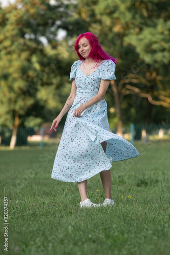 Young beautiful girl with red hair in nature in a beautiful summer dress.