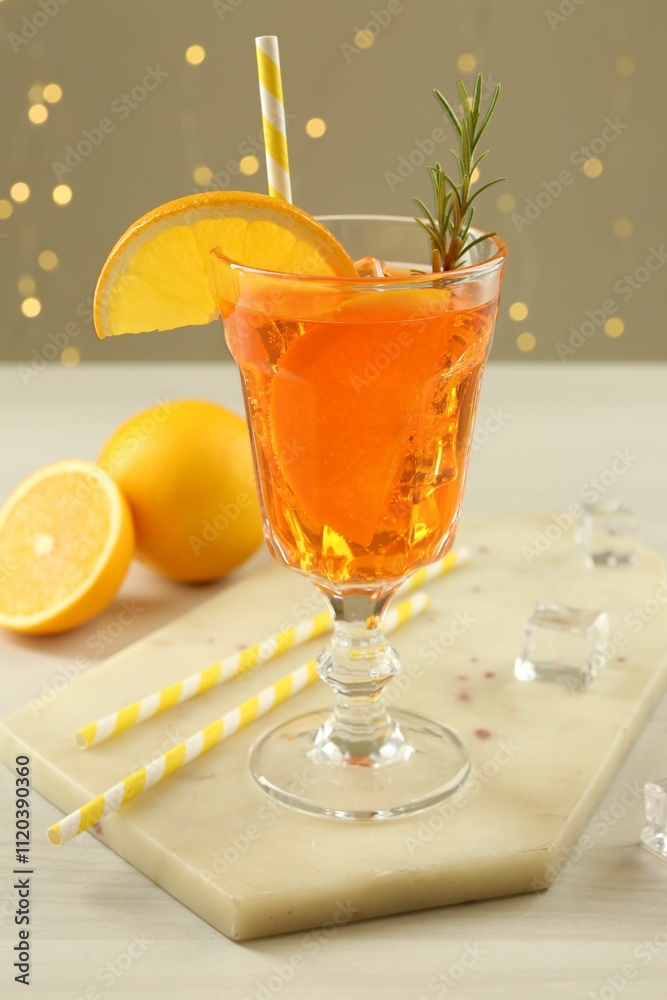 Fototapeta premium Tasty Christmas cocktail in glass on white wooden table against blurred lights
