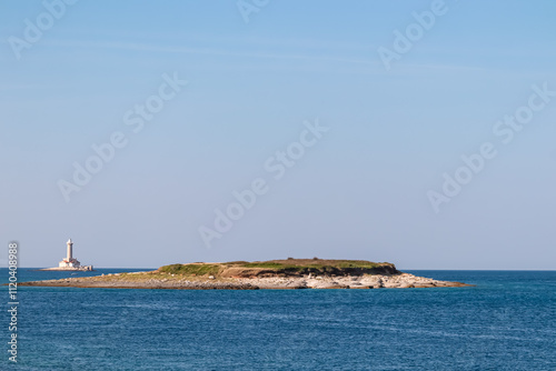 Scenic view of white lighthouse Porer seen from Cape Kamenjak National Park near Premantura, Istria, Croatia. Island Fenoliga in calm waters of the Adriatic Mediterranean Sea in summer. Seascape photo