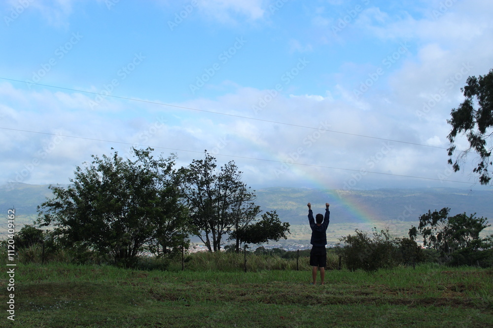 silhueta de homem com arco-íris ao fundo no céu