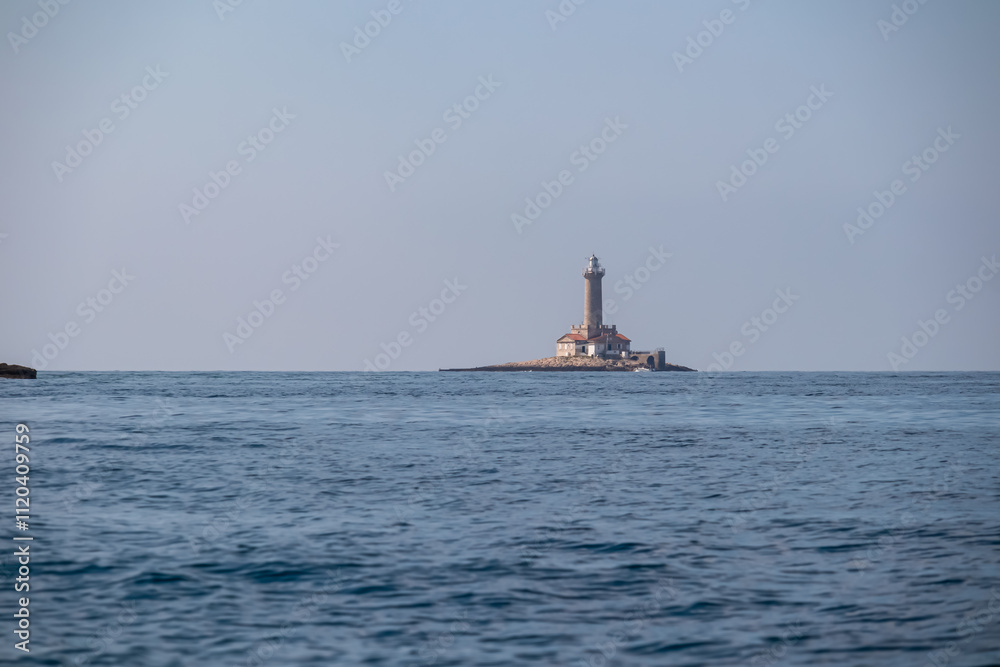 Scenic view of white lighthouse Porer build on small islet seen from Cape Kamenjak National Park near Premantura, Istria, Croatia. Calm water of the Adriatic Mediterranean Sea in summer. Seascape Scenic view of white lighthouse Porer build on small islet seen from Cape Kamenjak National Park near Premantura, Istria, Croatia. Calm water of the Adriatic Mediterranean Sea in summer. Seascape
