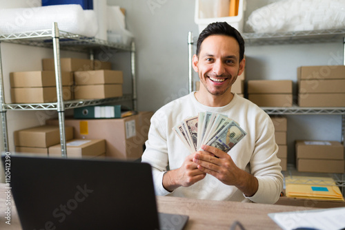 Entrepreneur managing online store and holding us dollar banknotes earned with laptop orders