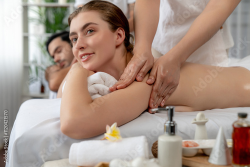 Caucasian couple customer enjoying relaxing anti-stress spa massage and pampering with beauty skin recreation leisure in day light ambient salon spa at luxury resort or hotel. Quiescent