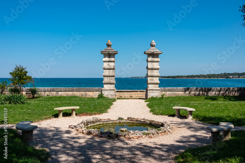 Idyllic scene at Samostan Monastery in Dajla, Istria, Croatia. Garden with a pair of stone pillars framing a view of the Adriatic Mediterranean sea. Tourist travel destination near Novigrad photo