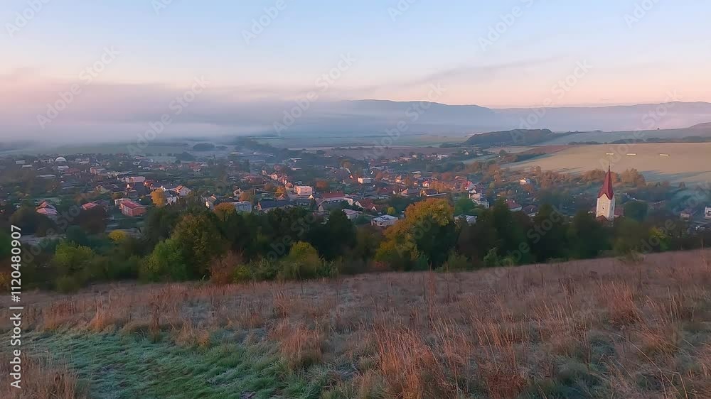 Autumn dawn in Krasnohorska Podhradie village and municipality in the Roznava District in Kosice Region, Slovakia. Nice morning view of Church of All Saints church. 4K video (Ultra High Definition). Autumn dawn in Krasnohorska Podhradie village and municipality in the Roznava District in Kosice Region, Slovakia. Nice morning view of Church of All Saints church. 4K video (Ultra High Definition).