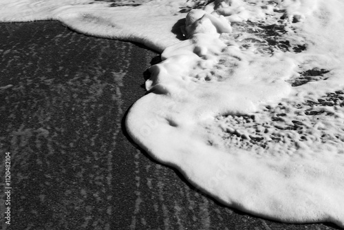Black and white study of foamy waves overlapping on a beach on Hutchinson Island, Florida
