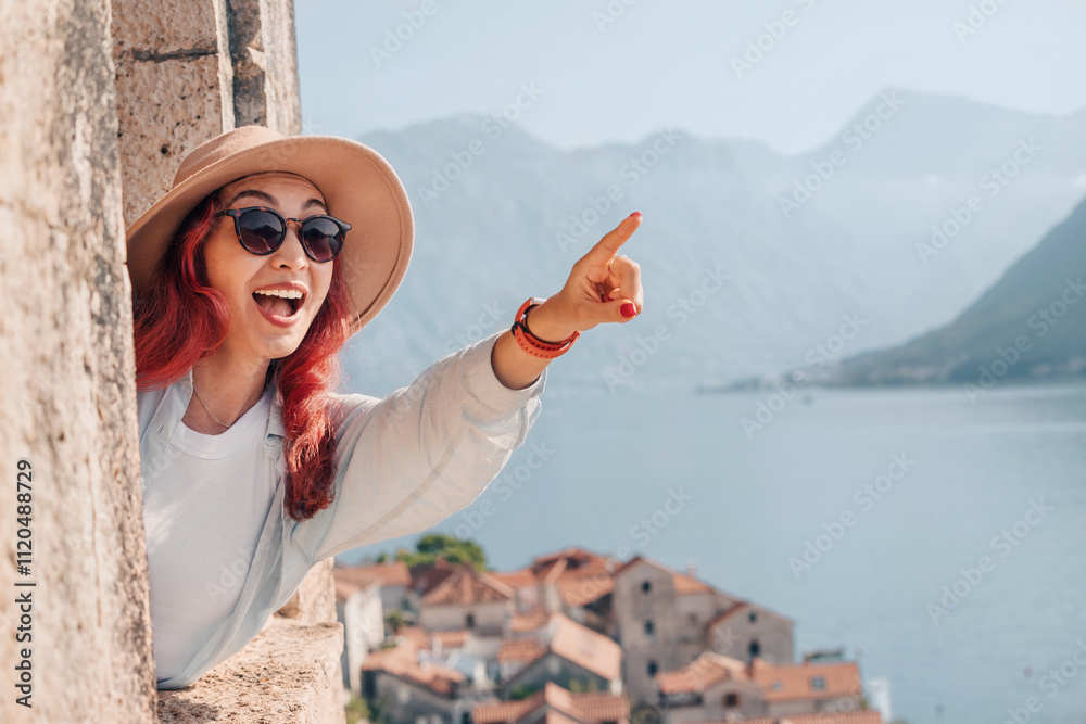 Happy tourist pointing at the bay of Kotor in Montenegro, enjoying the stunning view from the ancient city walls