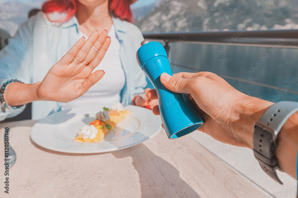Woman refusing salt while having breakfast at restaurant by the sea