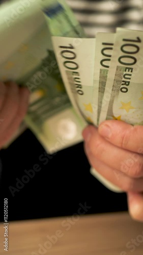 Vertical: White woman's hands holding euro banknotes counting the amount of money by hand. Woman counting euro cash after receiving unemployment benefit or salary