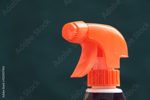 Orange color plastic spray bottle. Water sprayer. Dark green background. House-cleaning concept photo. photo