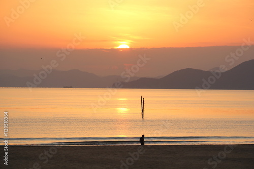 Image of people enjoying a beautiful sunset at Dadaepo Beach in Busan and a landscape image of sunset at sea
 photo