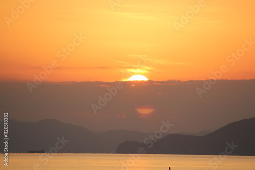 Image of people enjoying a beautiful sunset at Dadaepo Beach in Busan and a landscape image of sunset at sea
 photo