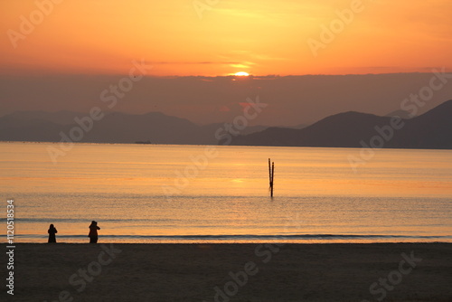 Image of people enjoying a beautiful sunset at Dadaepo Beach in Busan and a landscape image of sunset at sea
 photo