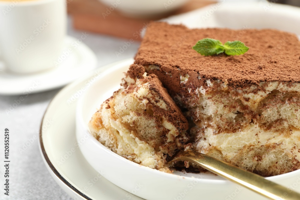 Delicious tiramisu with mint on light table, closeup