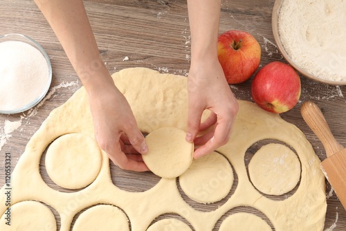 Woman making pirozhki (stuffed pastry pies) at wooden table, top view photo