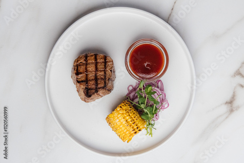 Grilled beef steak resting on a white plate, accompanied by vibrant grilled corn, sliced red onion, fresh microgreens, and a drizzle of savory sauce. Restaurant or cafe menu, cookbook recipe


