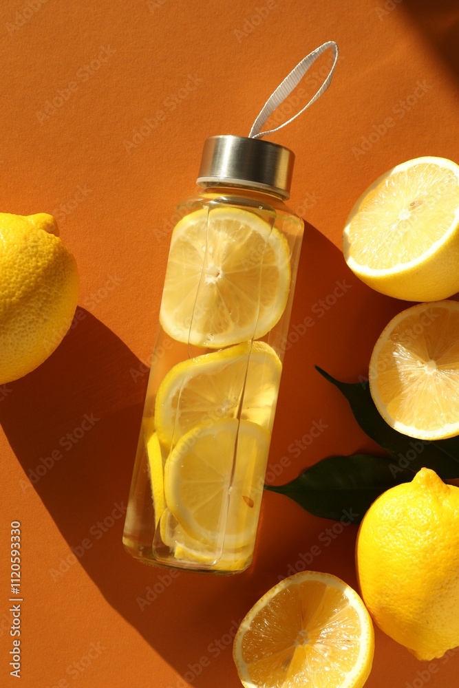 Lemon water in bottle, fresh fruits and leaves on brown background, flat lay Lemon water in bottle, fresh fruits and leaves on brown background, flat lay
