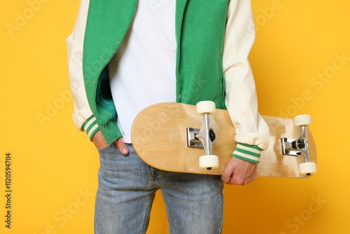 Man with skateboard on orange background, closeup