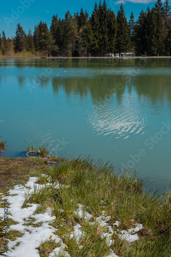 Beautiful blosko jezero or bloke lake in early spring, with cold lake, green grass and snow patches still visible... photo