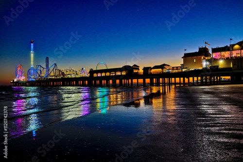 Galveston, Texas - 11-23-2024. An amusement park on a large pier looking out into the Gulf of Mexico.  The bright lights reflect in the water as it laps on shore.