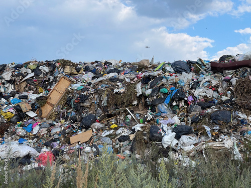 A view of a landfill where waste fills the space and hangs over the ground