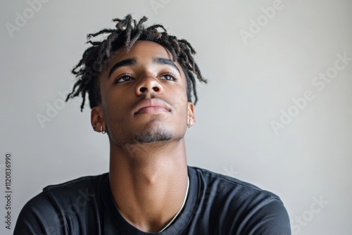 Contemplative Young Man with Dreadlocks Gazing Upward in Natural Light