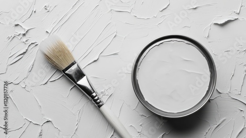 Grey paint can with brush on textured white background showcasing strokes of paint in an artistic flat lay composition photo