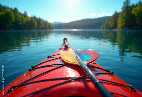 The nose of the red kayak over the surface of the lake and a paddle lying across the kayak