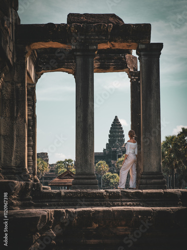 A young woman admiring the famous Hindu-Buddhist temple Angkor Wat located near Siem Reap, Cambodia.