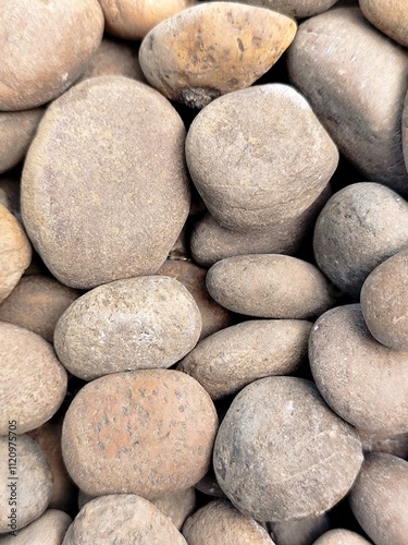 Smooth stone wall background with pebbles on the beach and a textured rocky surface
