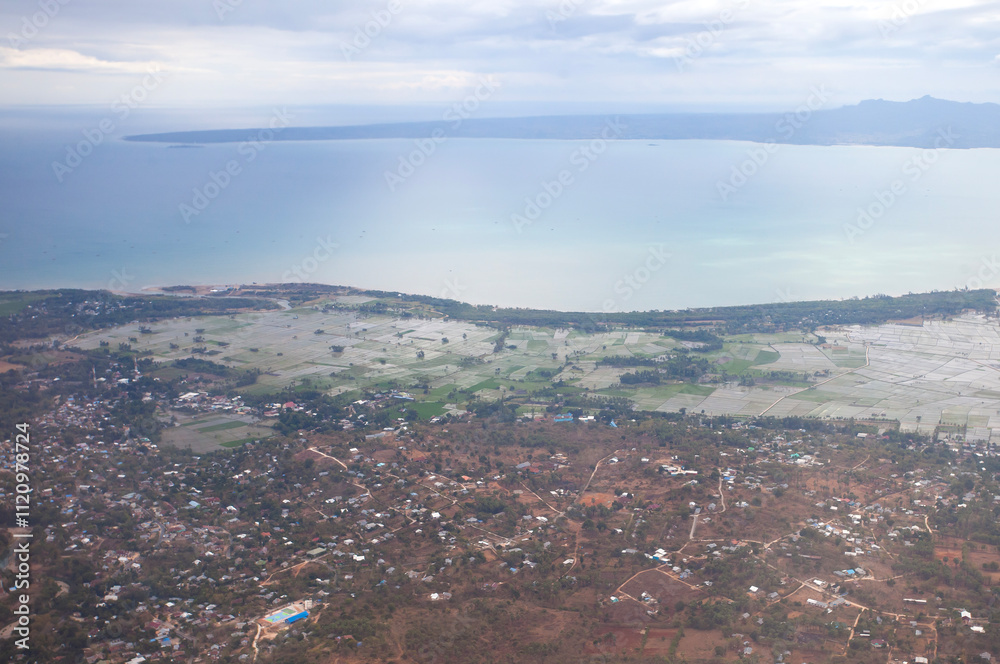 Obraz premium Aerial view of Kupang city, the capital of East Nusa Tenggara Province, Indonesia. Urban landscape with coastline, settlements, built-up areas and some agricultural areas.